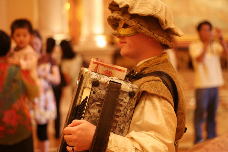 a young man in costume and blindfold holds an accordon