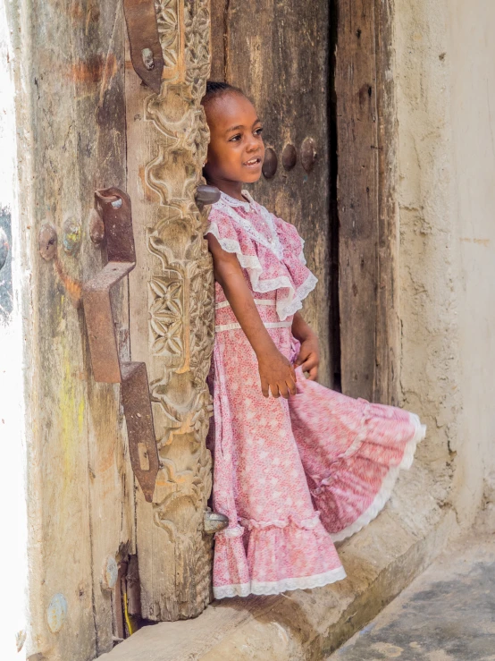 a  standing near a wall wearing a pink dress