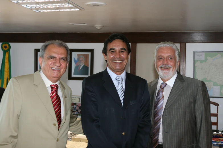 three men wearing business suits and ties in a living area