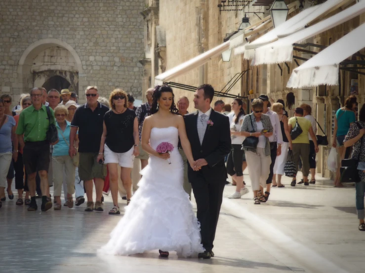 a bride and groom walk on a crowd of people