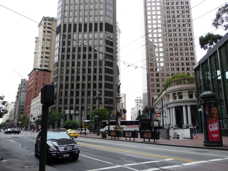 cars are driving through the city intersection in front of tall buildings