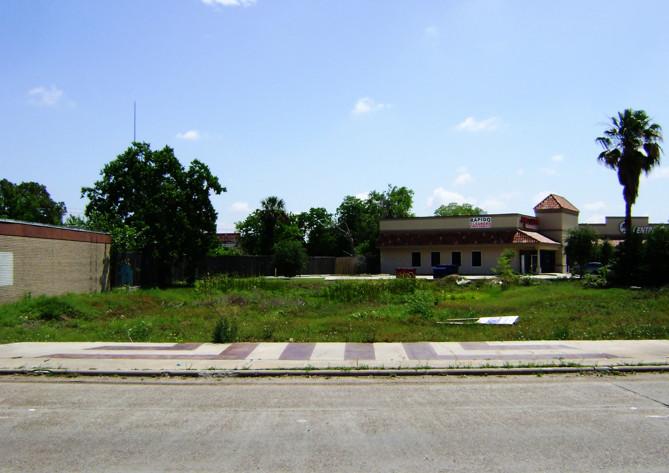 an intersection with a road, tree, and brick building