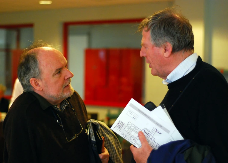 two men standing close together with papers