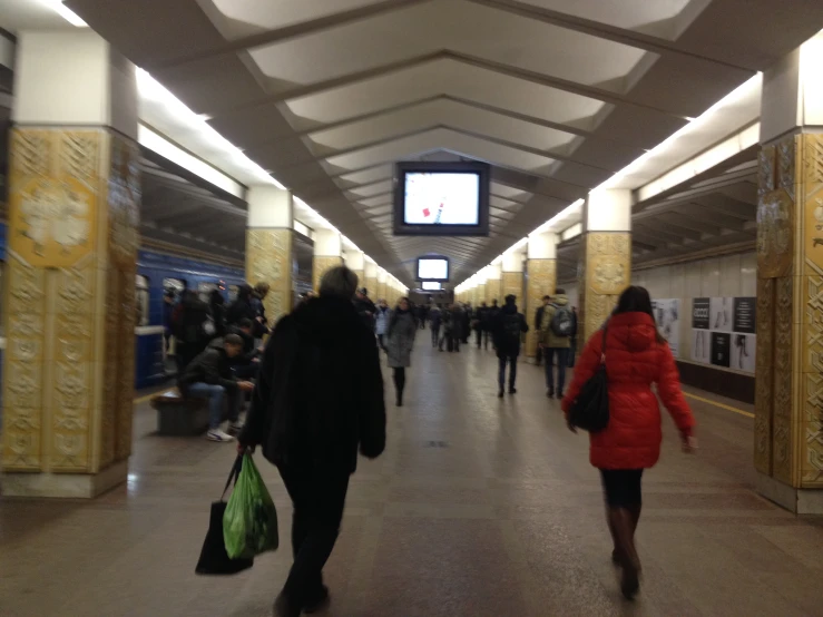 people walking through an empty subway station with one man carrying luggage