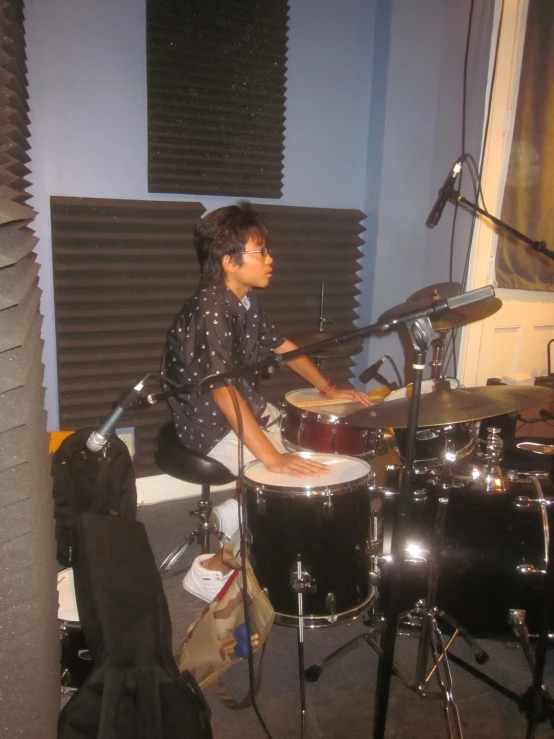a boy playing the drums in a recording room