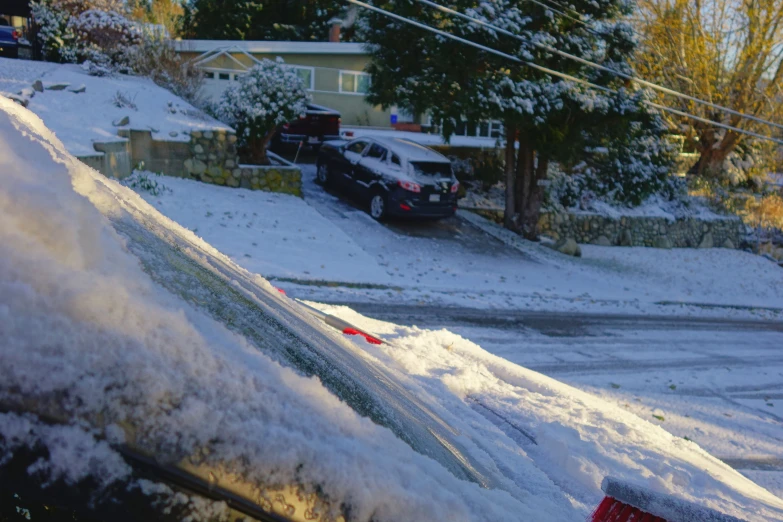 cars are parked in the driveway while the snow covers the sidewalks