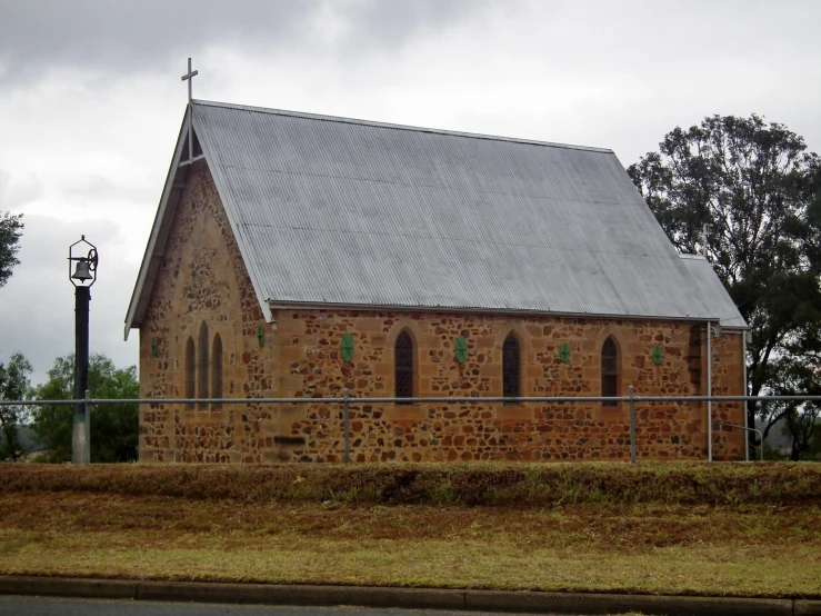 an old church with grass and a fence behind it