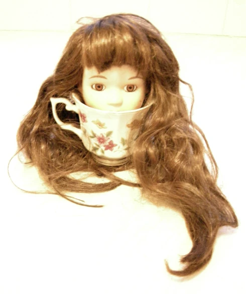 a very long brown haired doll with a cup