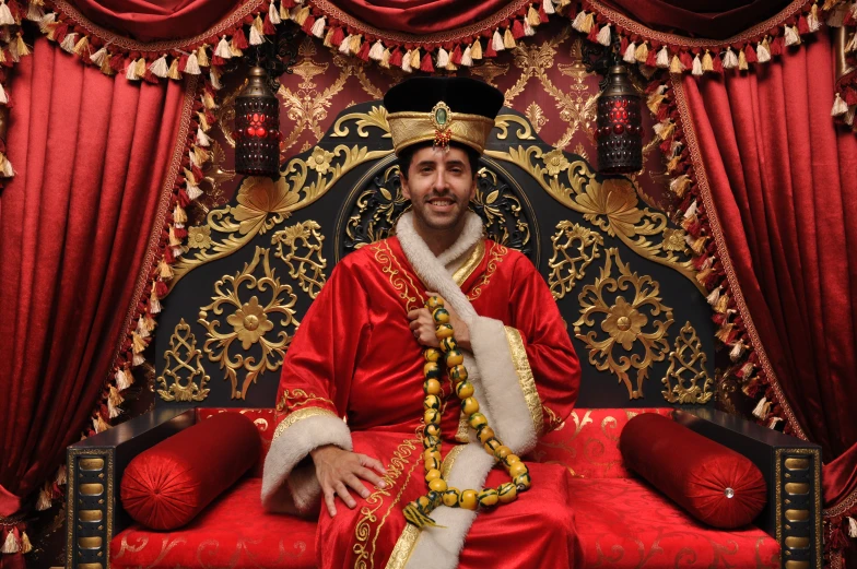 a man dressed in elaborate red clothing sitting on a throne