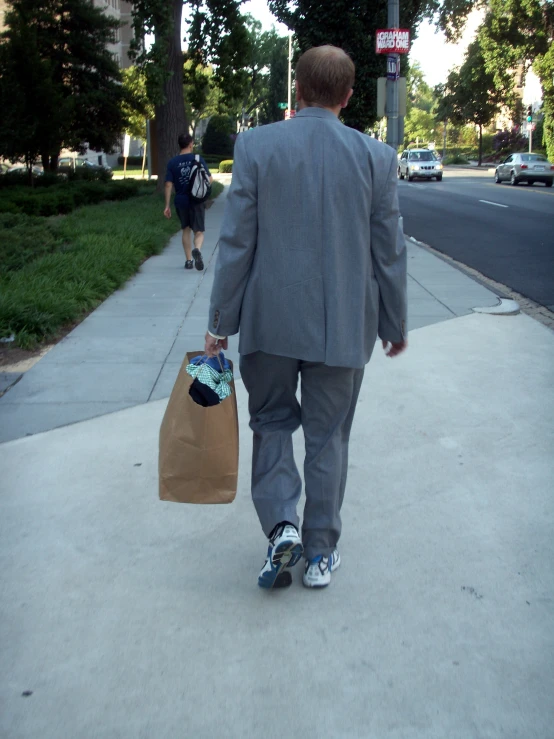 a person is walking down the sidewalk with a bag
