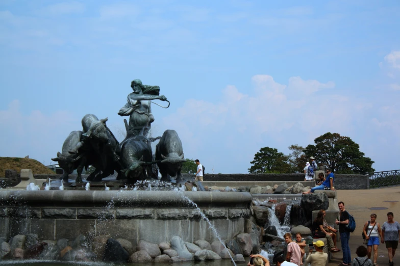 a fountain in front of a beach with people standing around it