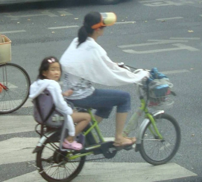the woman is riding her bike and hing the child behind