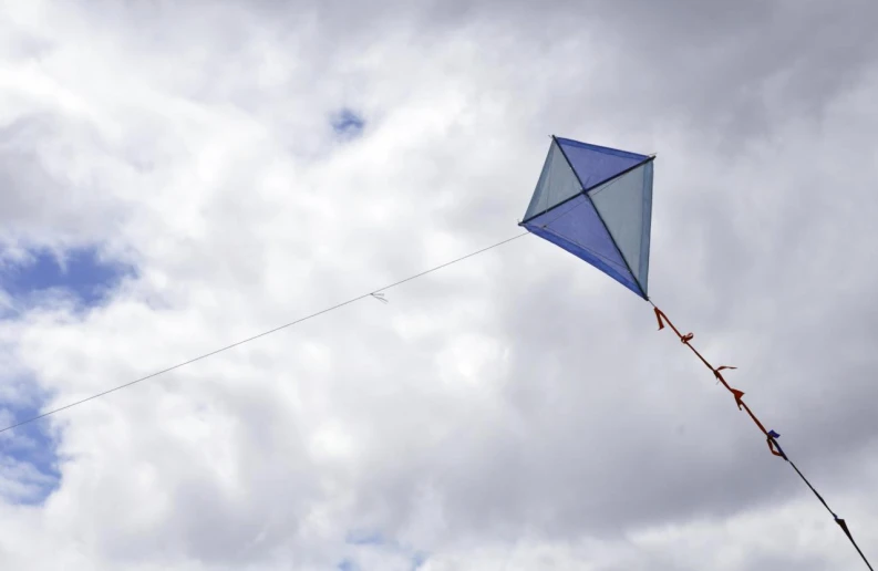 a kite flies in the cloudy sky on a string