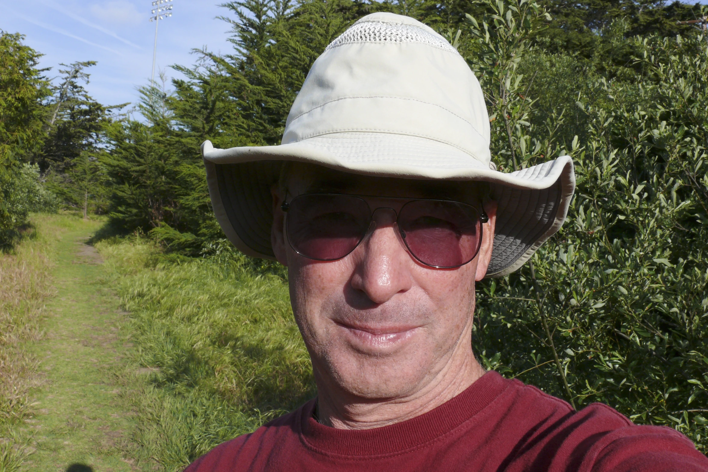 man in hat and sunglasses standing on a dirt path