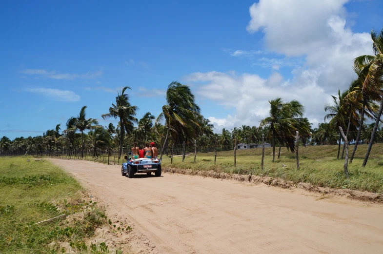 a man drives his small vehicle down a dirt road