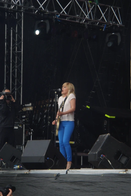 a lady in blue pants singing on stage