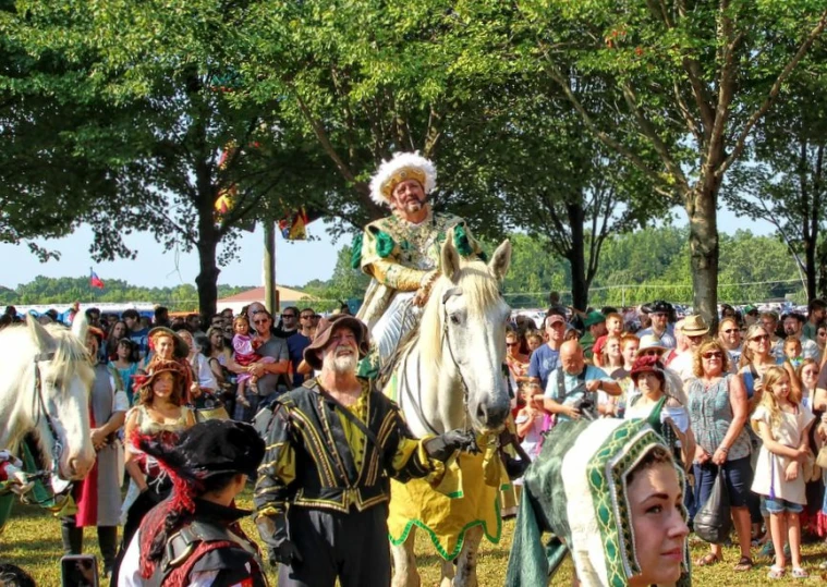 a parade with people standing and sitting in front of horses