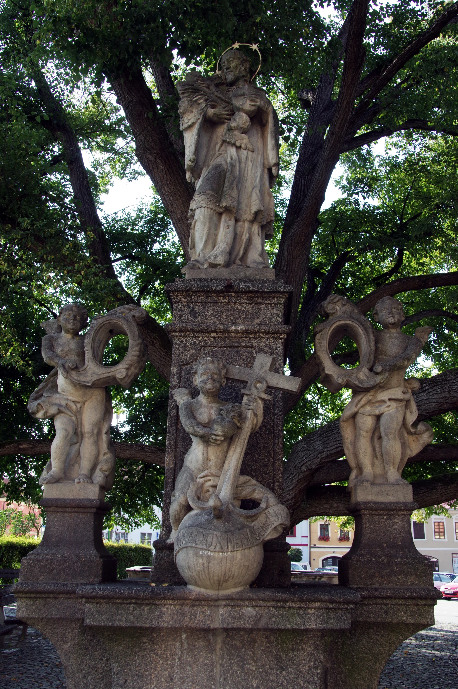 a decorative fountain in front of a tree with some statues