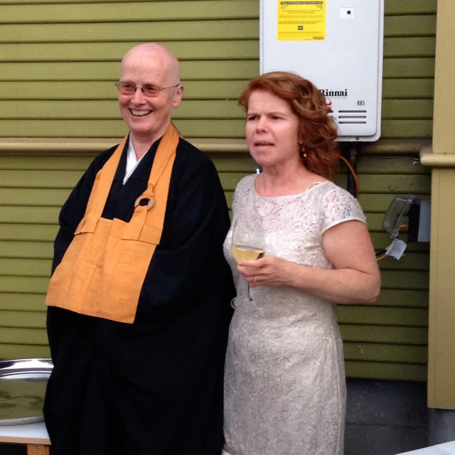 two people standing near each other and one woman holding a glass