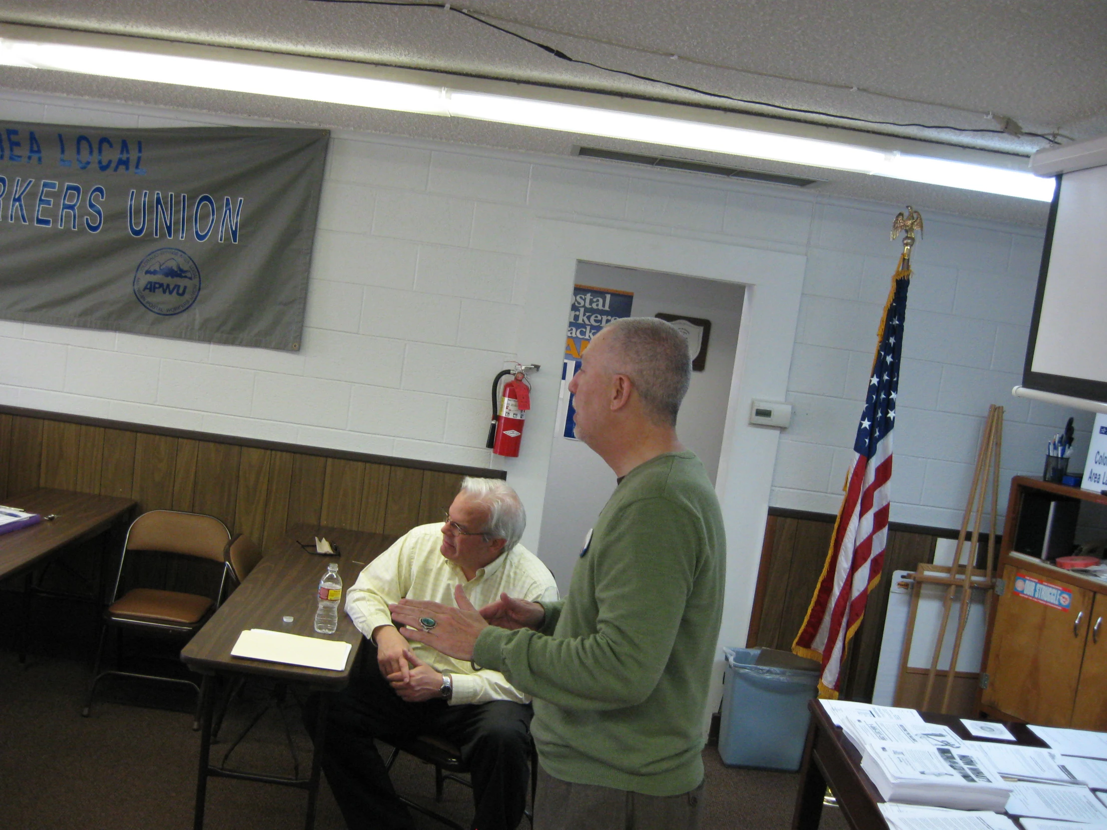 two men standing in front of tables in a room