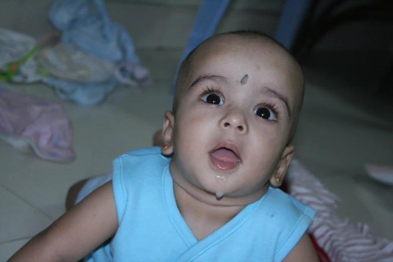 a baby is sitting on the floor looking up