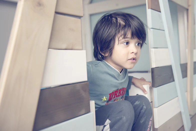 small boy with brown hair sitting up in a bunk bed