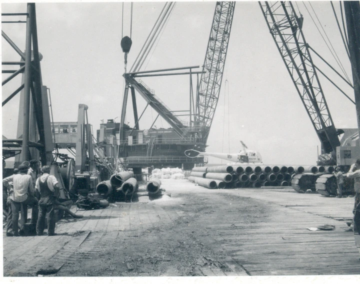 men standing on a dock with lots of steel pipes