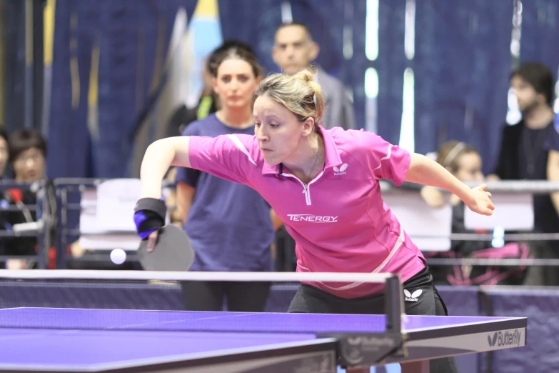 a woman reaching to hit the ball on a ping pong table