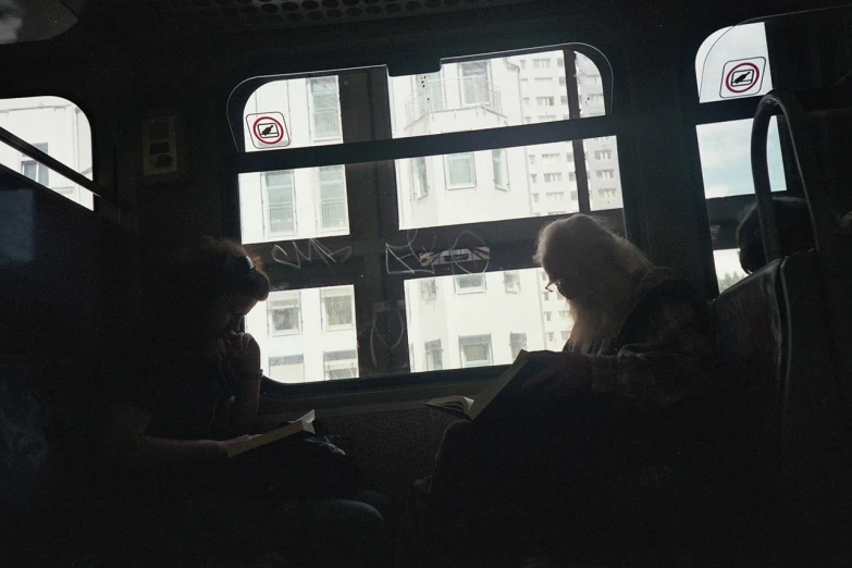 two people are sitting on a bus looking out the window