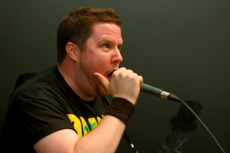 a man on stage holds his chin to his mouth and a microphone