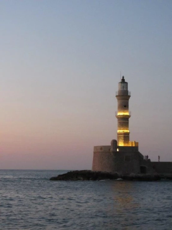 a lighthouse lit up at night on the water
