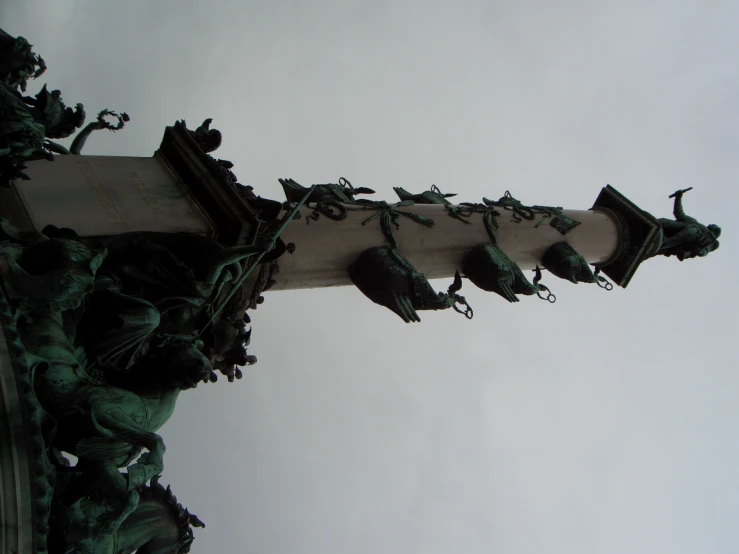 a pillar has many birds on it and has green leaves