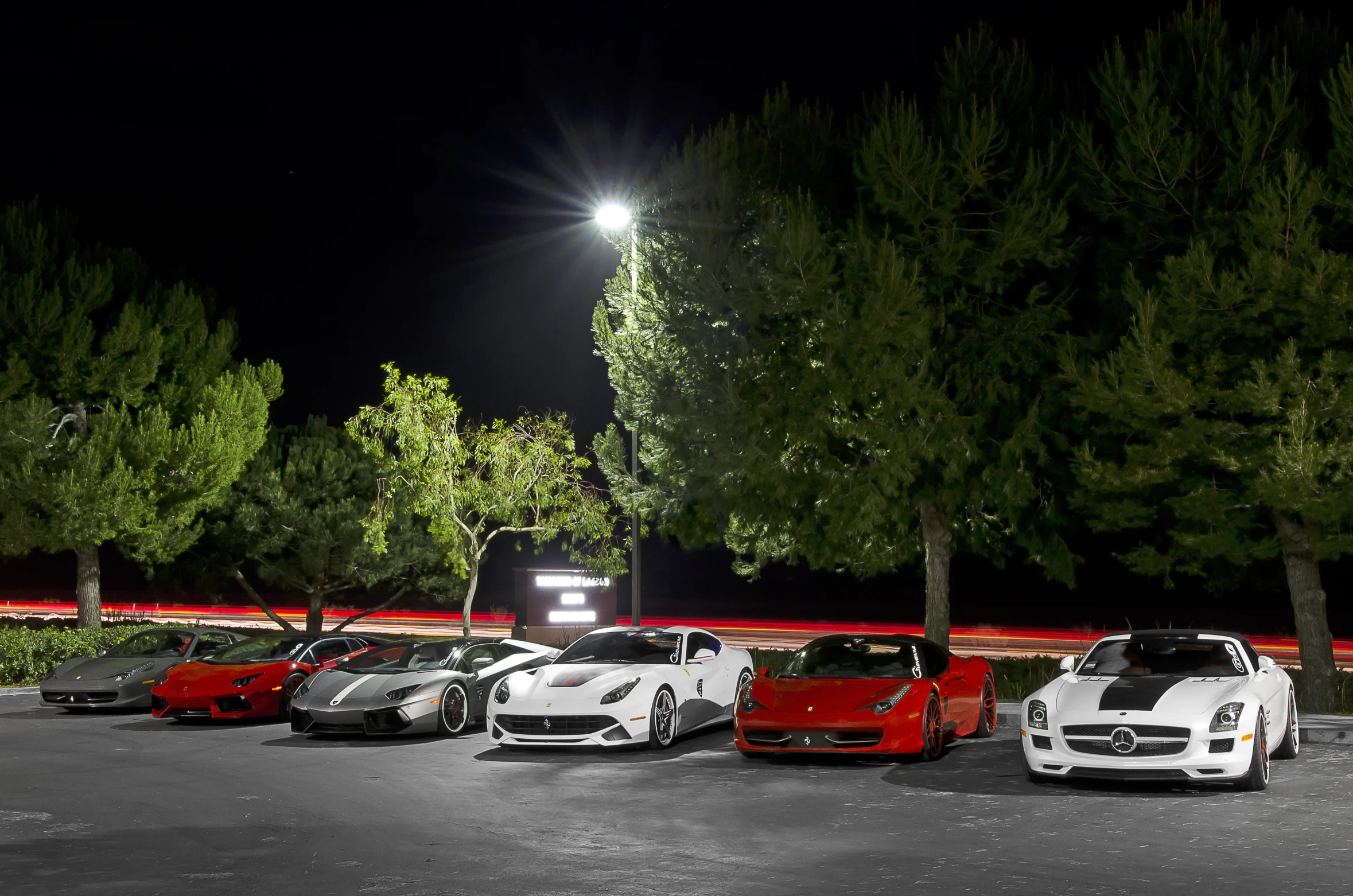 a parking lot filled with exotic cars under a night sky