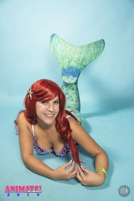 a girl poses next to a mermaid tail