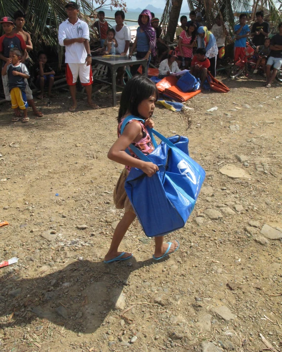 the small girl is carrying a bag with her feet