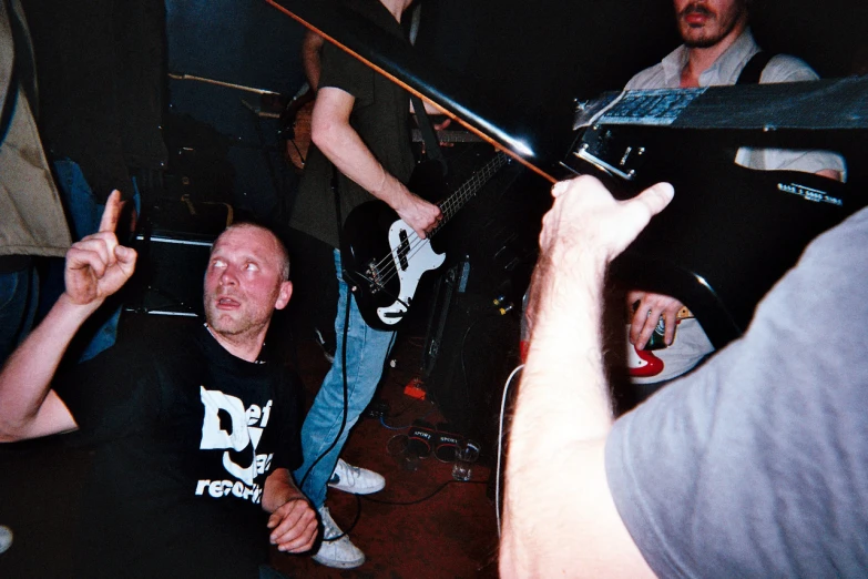 people sitting on a floor and one man on a guitar