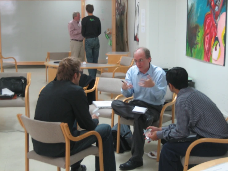 three men sitting and talking in an office