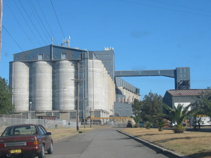 cars parked on the side of a road in front of grain storage buildings