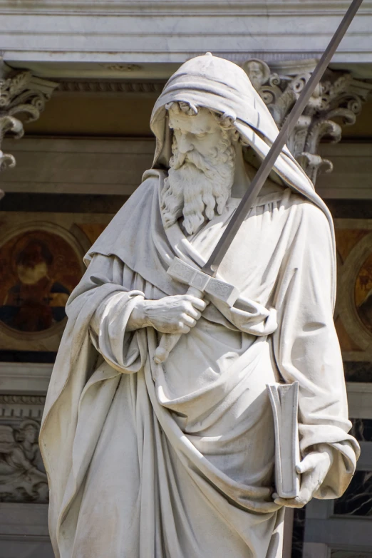 a statue of a man in white robe holding a sword