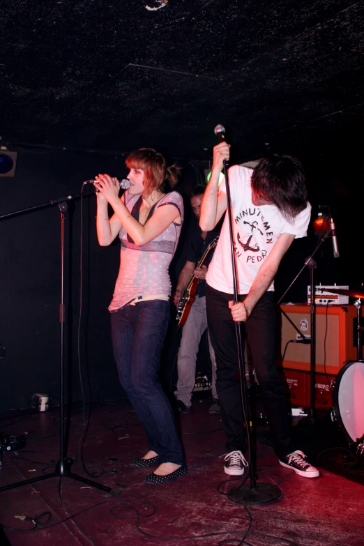 two people standing on stage with microphones in hand