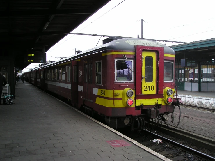 a red and yellow train pulls into a train station