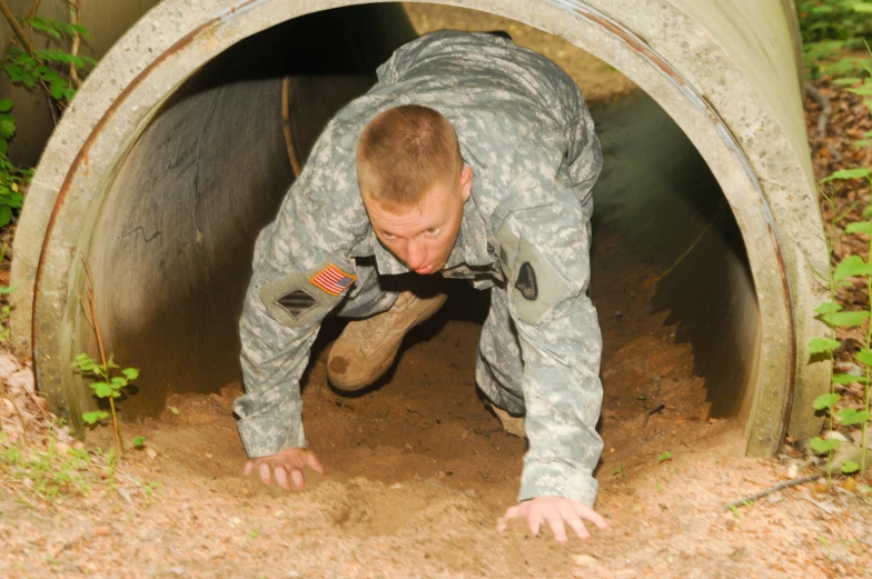 soldier with goggles and helmet climbing into a tunnel