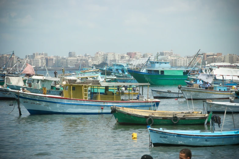 several boats parked in the ocean near city buildings