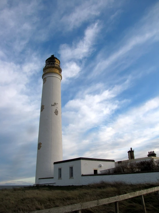 a lighthouse with a white and yellow top on a hill