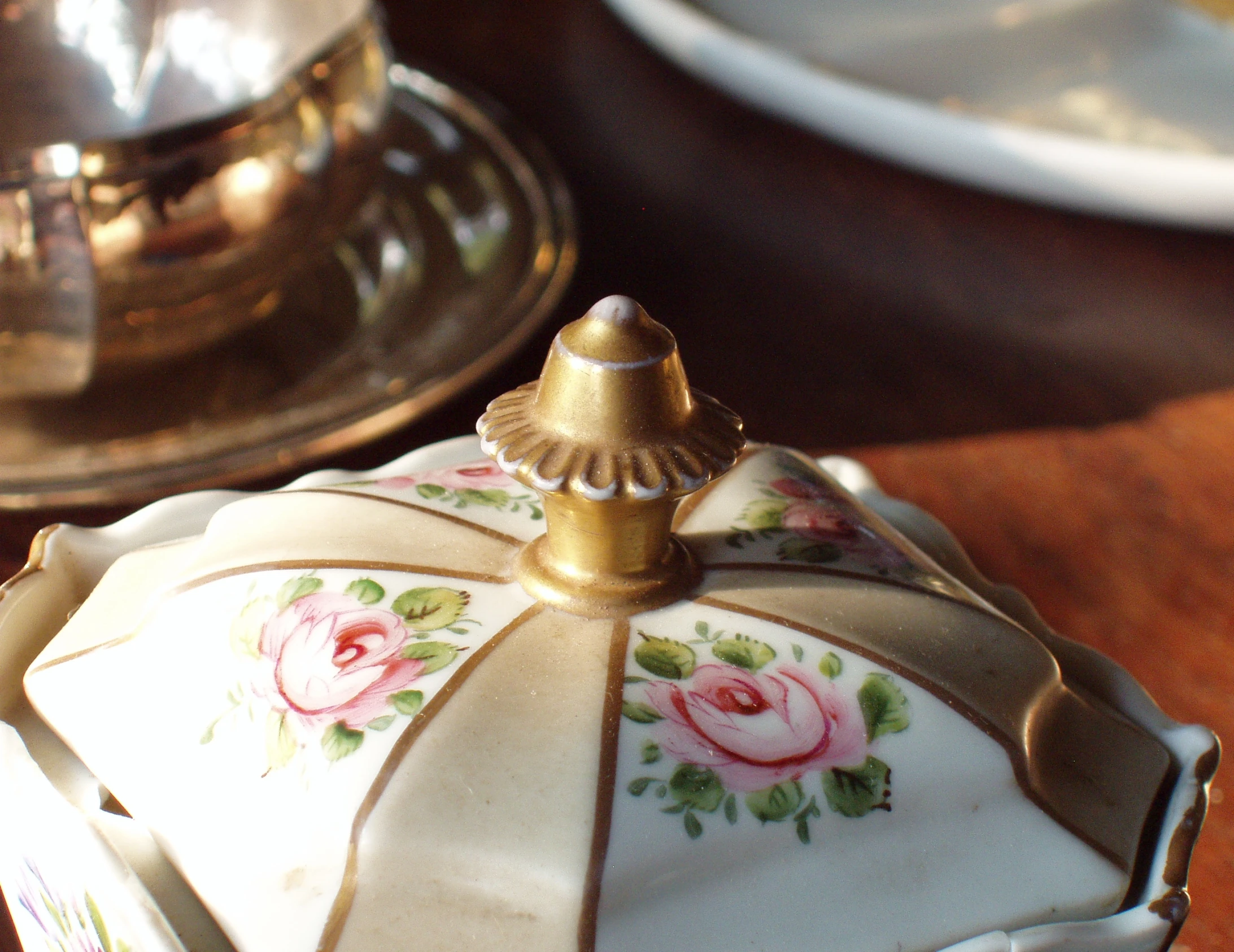 a fancy white and gold teapot with a rose design