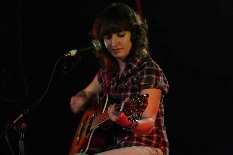 a woman holding an acoustic guitar and singing