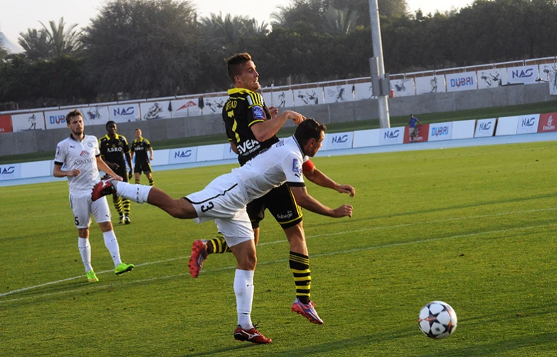 two men kick the ball in front of the opposing players