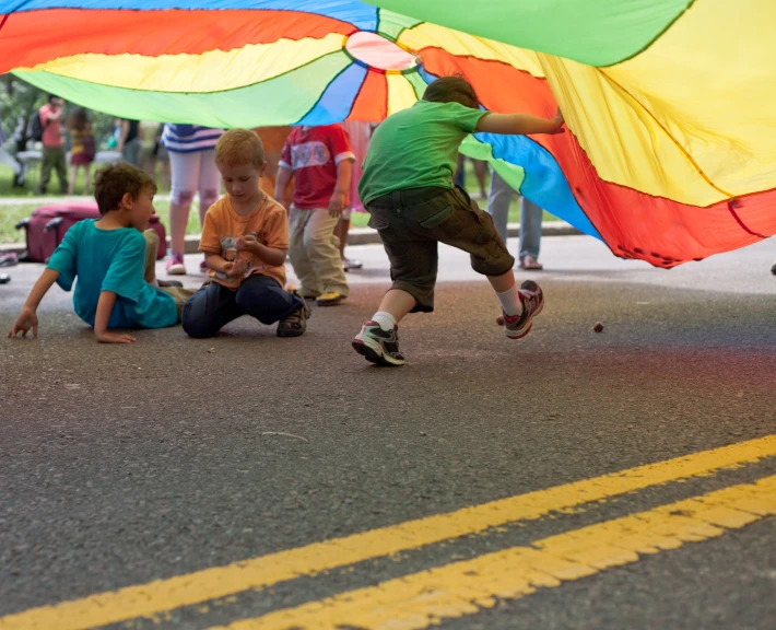 three s underneath a kite are sitting on the side of the road