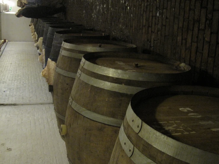 some wooden barrels in a warehouse near brick floors