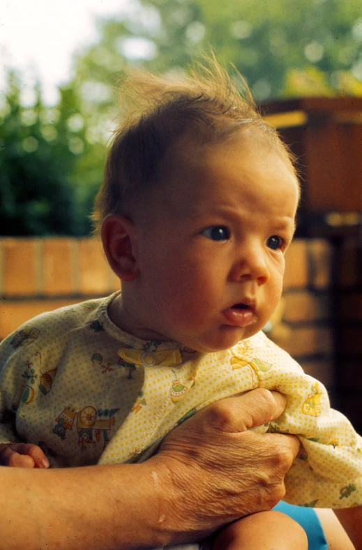 a baby is held by an older mans hand